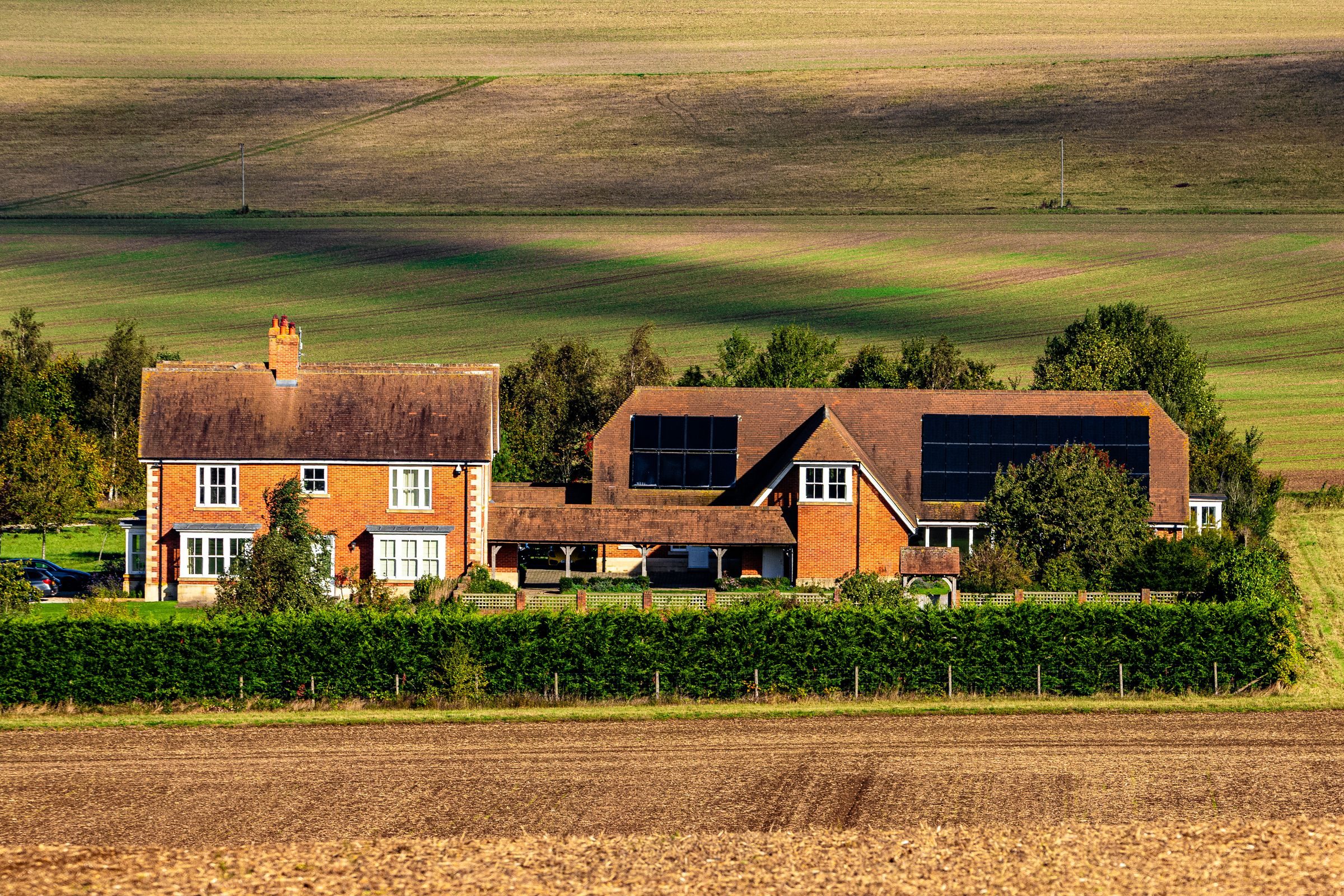 An English farmhouse with solar panels on its outbuilding roofs