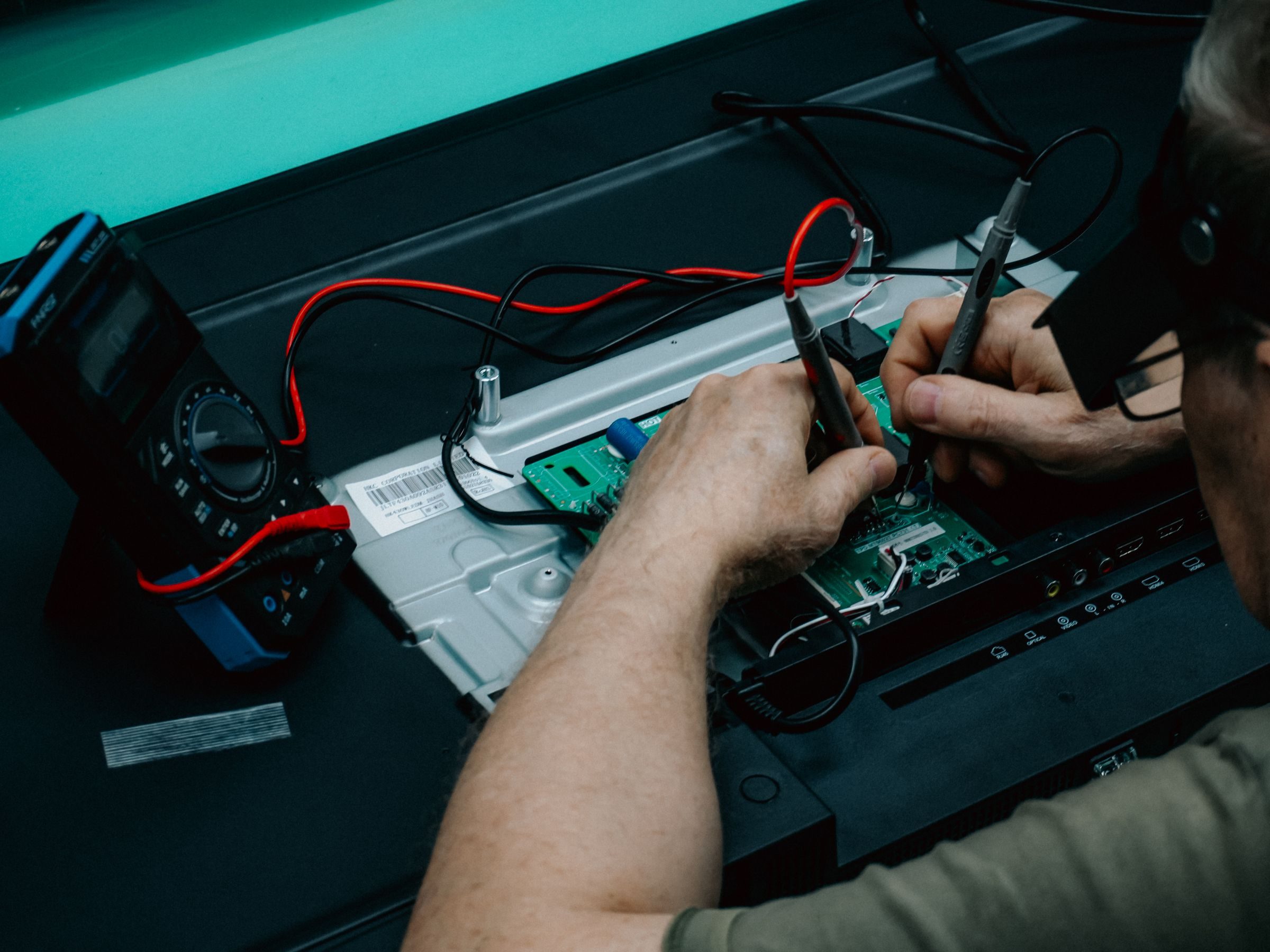 Hands testing the inside of an inverter with a multimeter