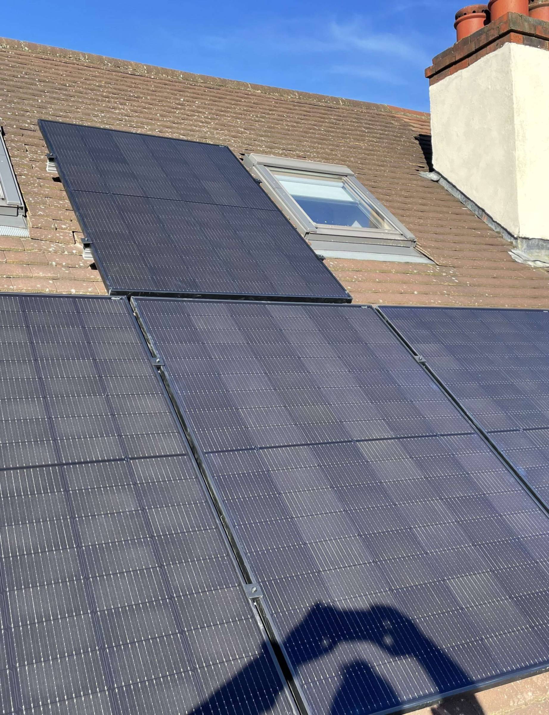 Black solar panels fitted around the roof windows of a home we installed