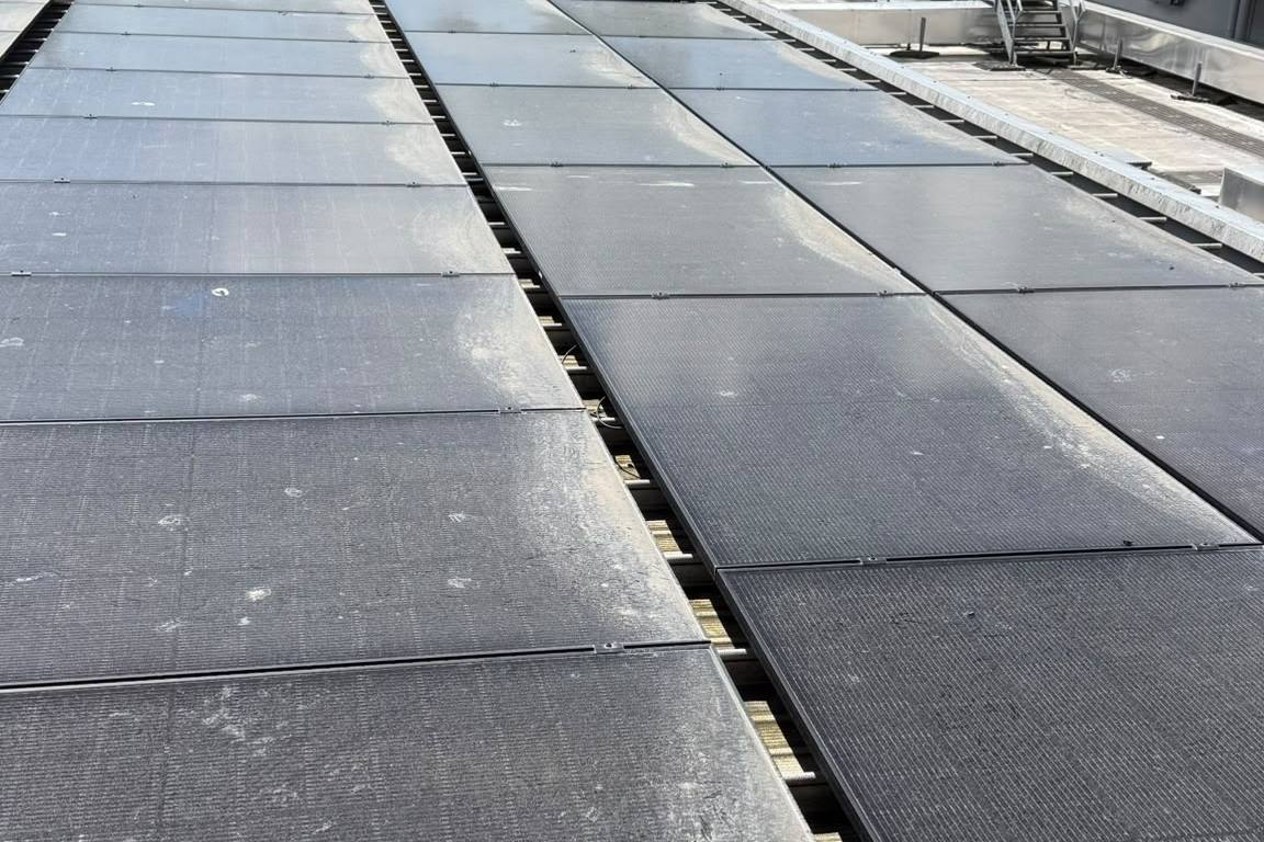 Solar panels coated in grime and bird droppings on a commercial roof