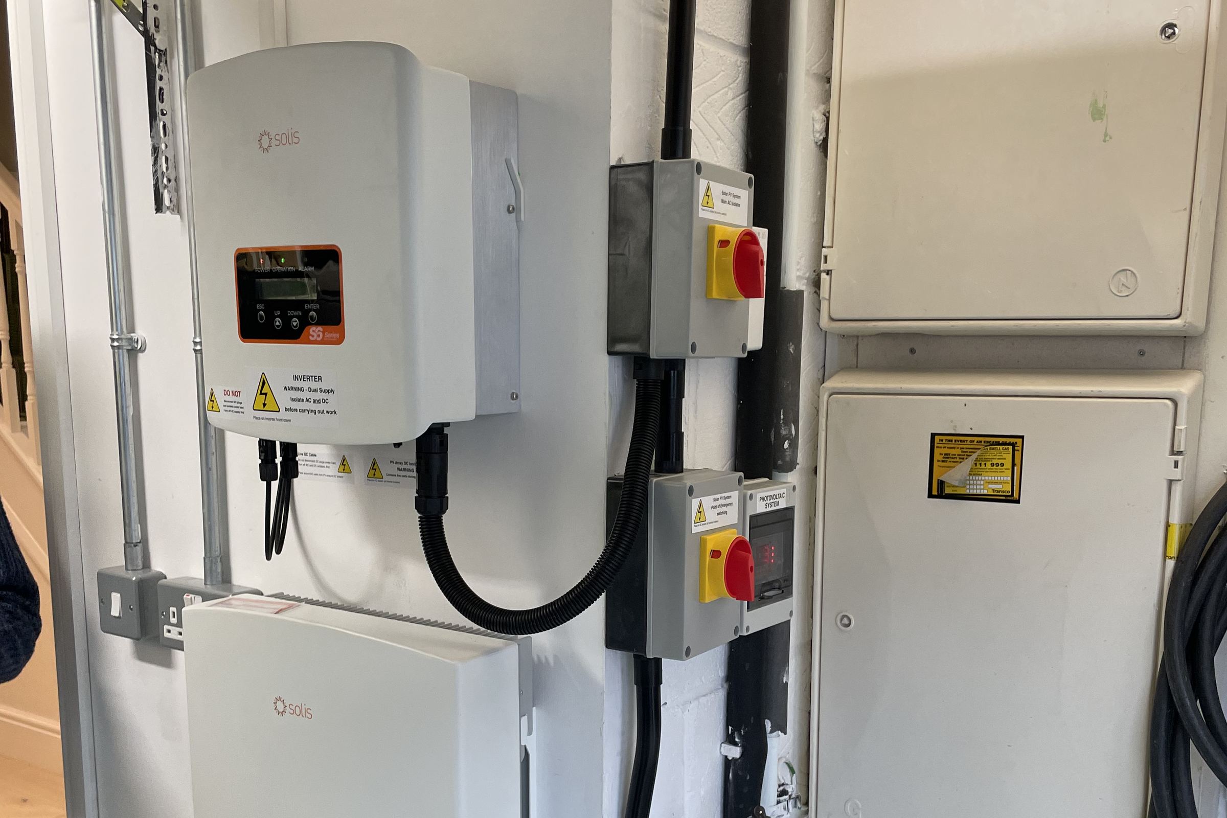 An inverter, isolator switches and a battery we connected on a garage wall