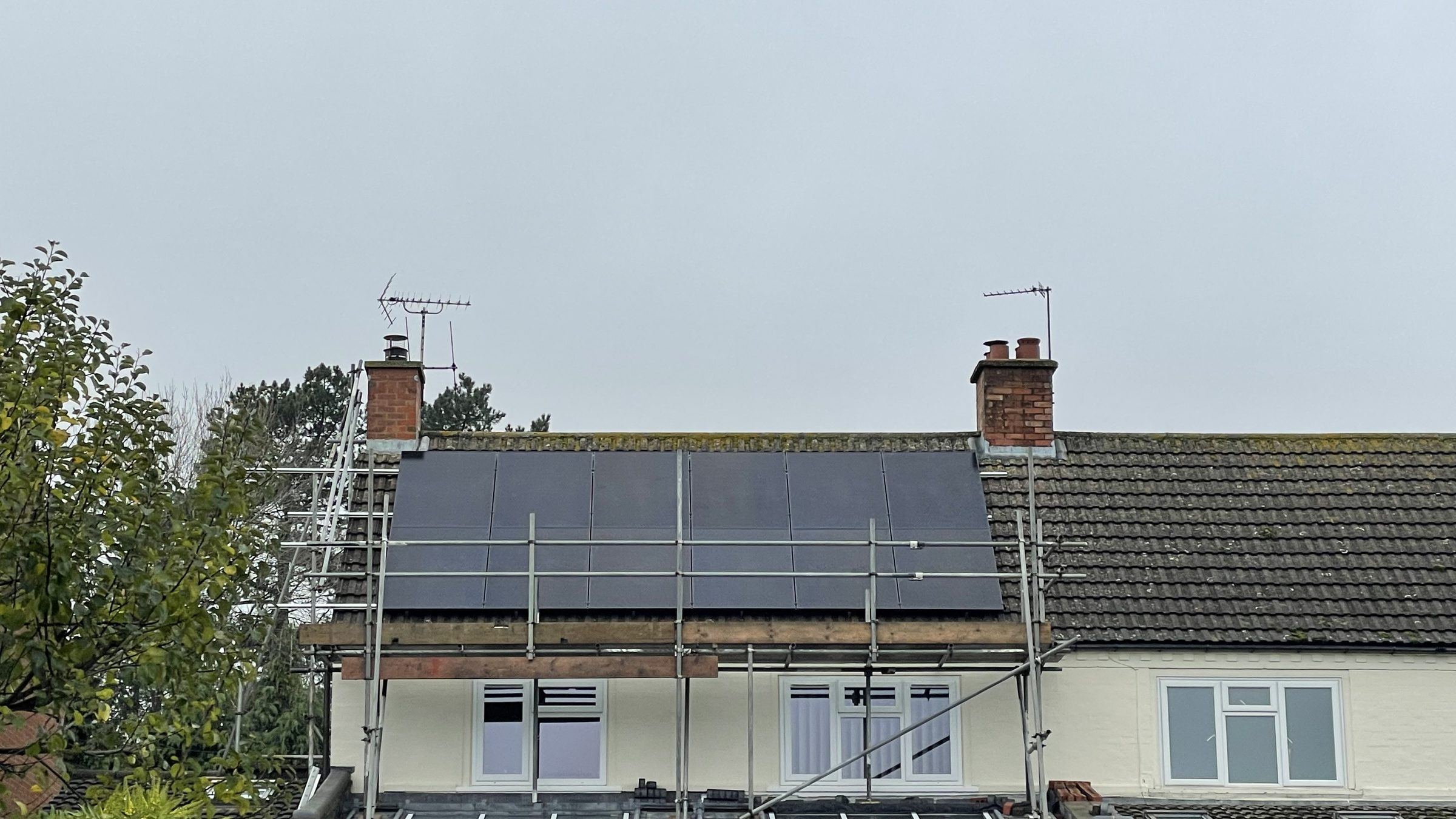 A house with scaffolding still up and a new black solar array on the roof