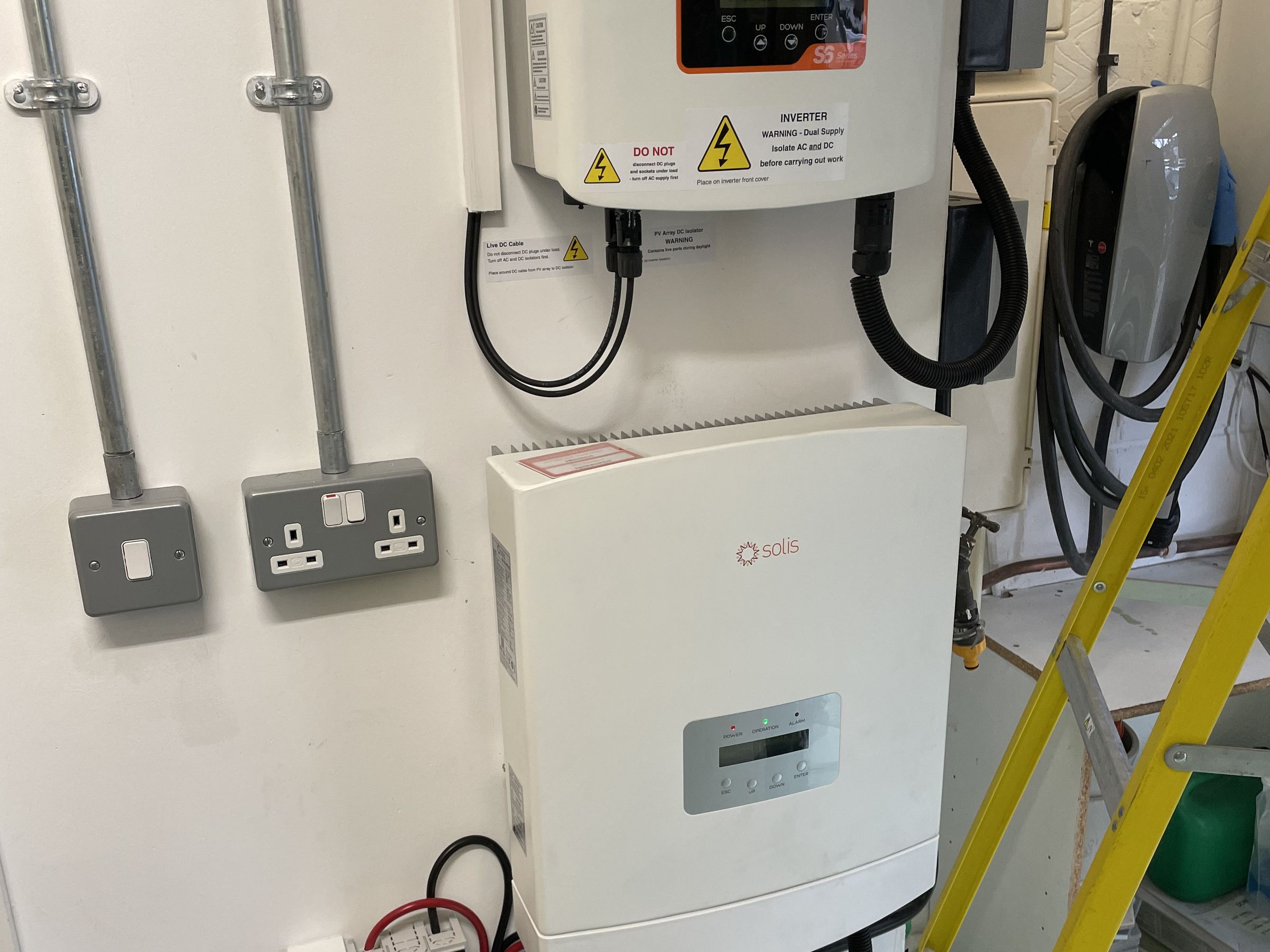 A single hybrid inverter with its battery, isolators and meter, fitted on a garage wall