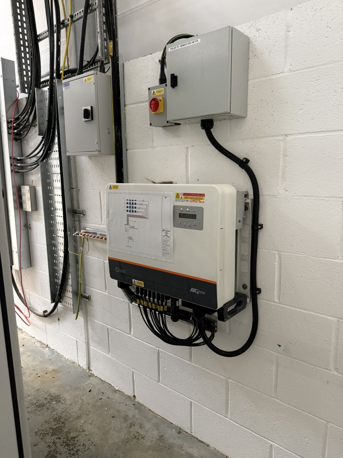 A wall-mounted inverter with its isolator, fitted by DB Energy
